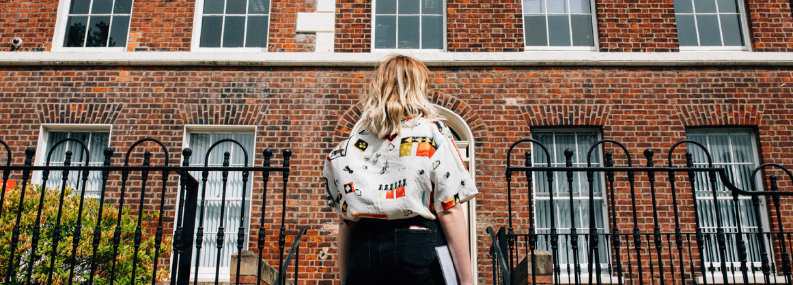 young female student walking into a Queen's university building