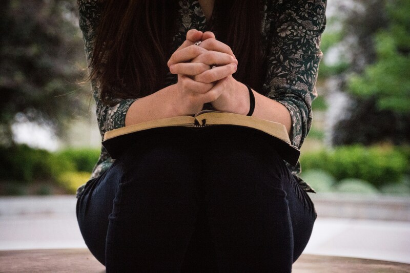 Woman praying with book on her lap